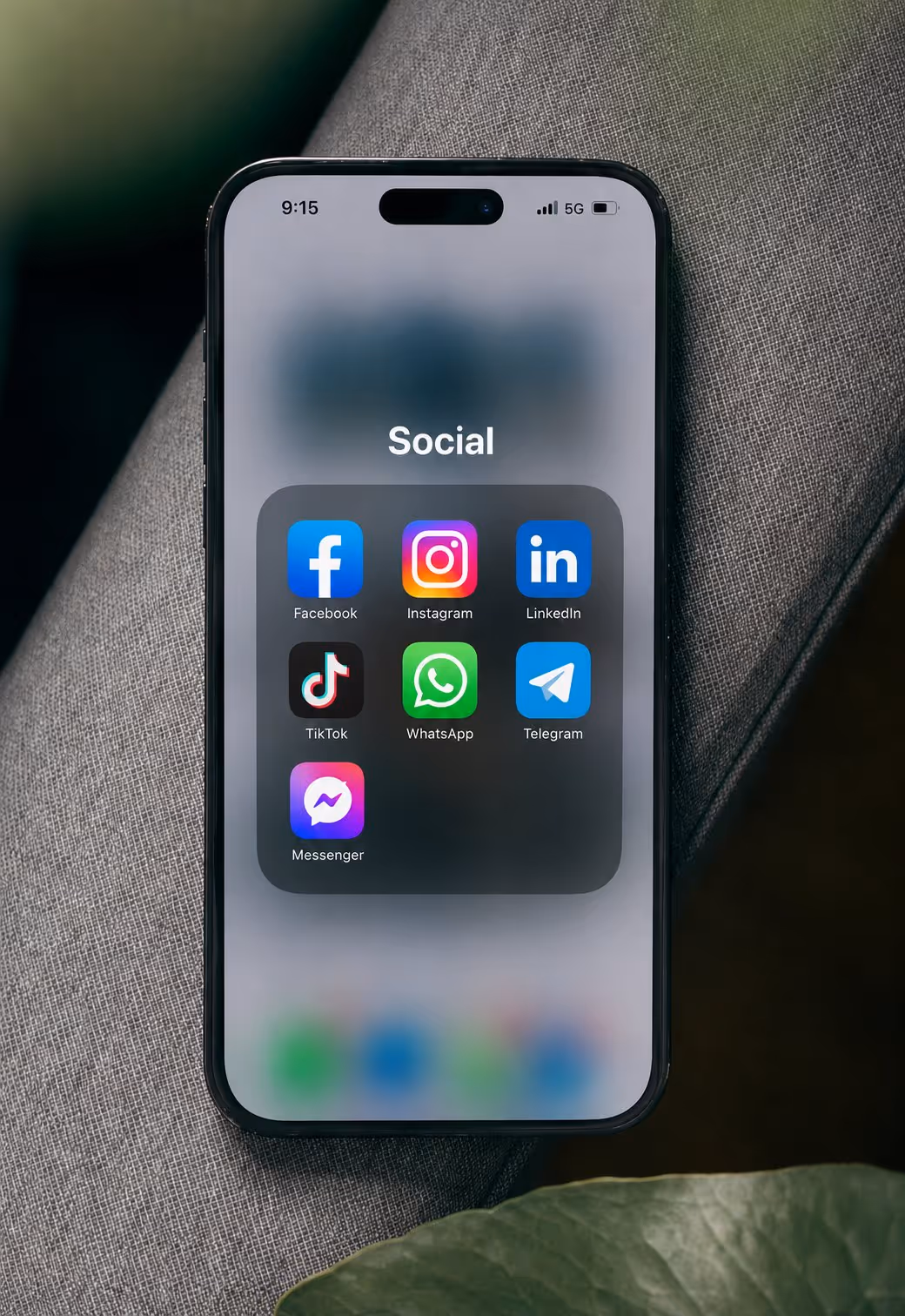 A smartphone on a couch showing the Social app folder